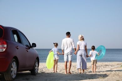 Photo of Family with inflatable rings near car at beach