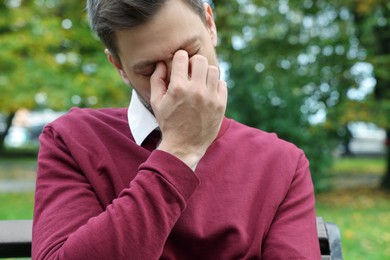 Photo of Sleepy tired man on bench in beautiful green park, closeup