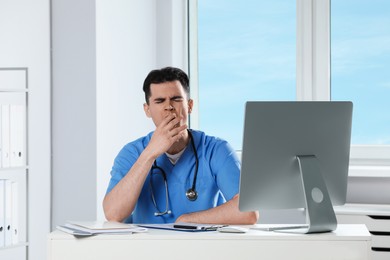 Photo of Exhausted doctor yawning at workplace in hospital