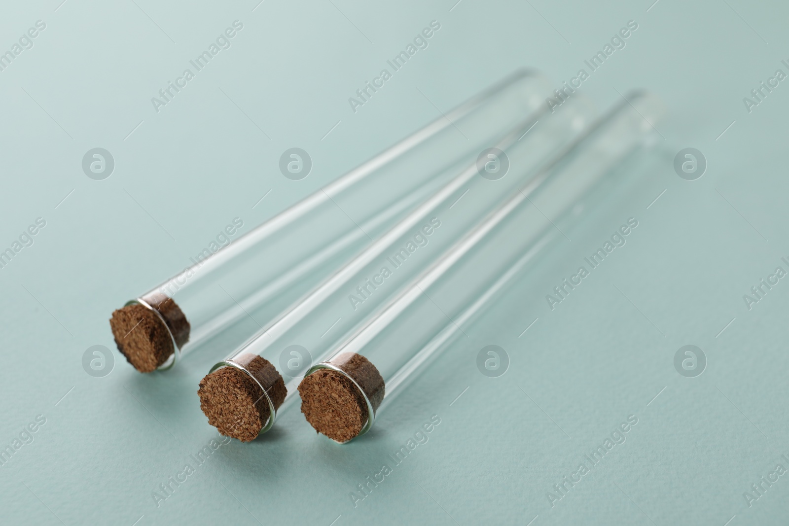 Photo of Test tubes on turquoise background, closeup. Laboratory glassware