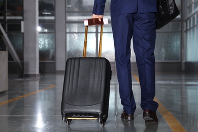 Businessman with black travel suitcase in airport