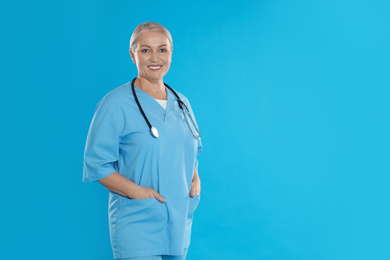Photo of Portrait of mature doctor with stethoscope on blue background. Space for text