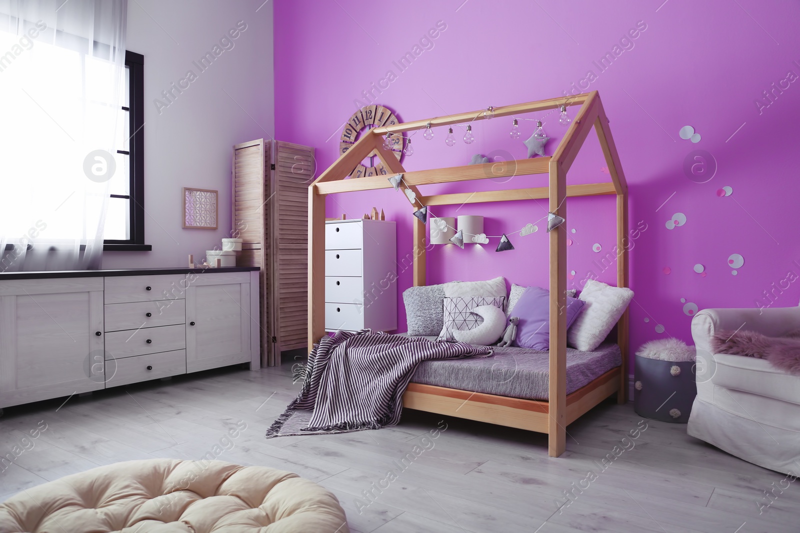 Photo of Child's room interior with comfortable bed and garland