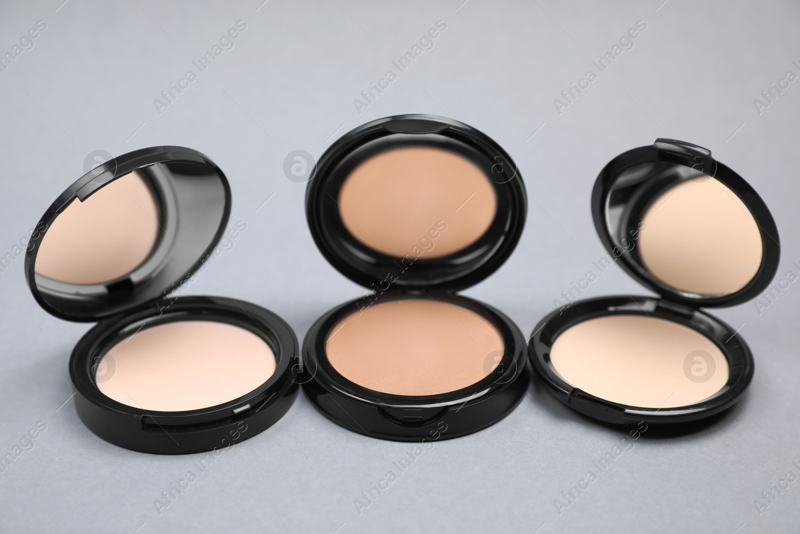 Photo of Open face powders with mirrors on light grey background