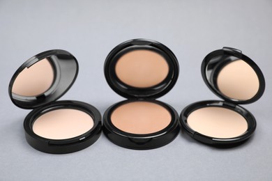 Photo of Open face powders with mirrors on light grey background