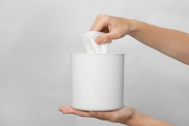 Photo of Woman taking paper tissue from holder on light background, closeup