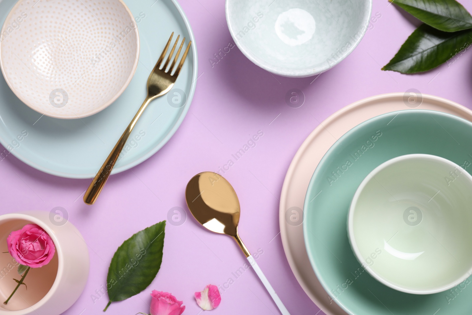 Photo of Beautiful table setting with flowers and leaves on pink background, flat lay