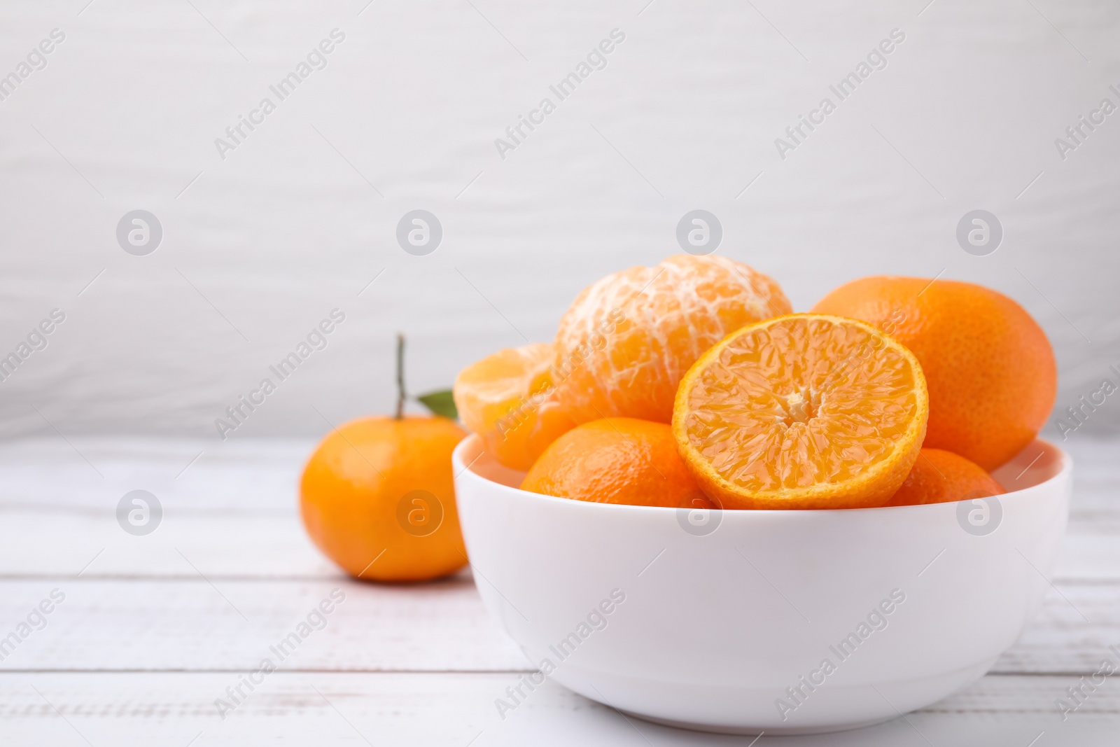 Photo of Fresh juicy tangerines on white wooden table, space for text