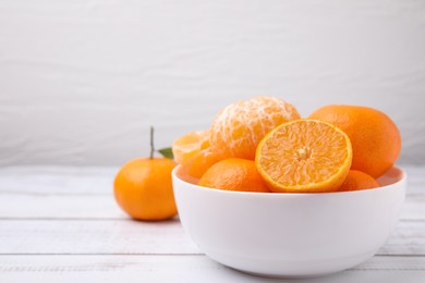 Photo of Fresh juicy tangerines on white wooden table, space for text