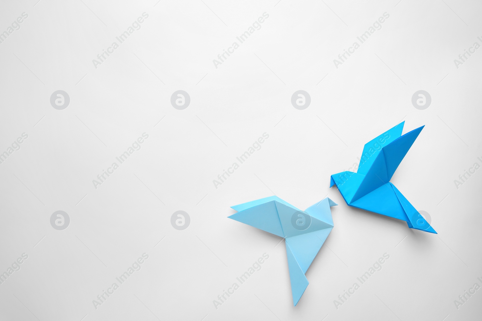 Photo of Origami art. Colorful handmade paper birds on white background, flat lay. Space for text