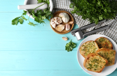 Photo of Slices of toasted bread with garlic and herbs on blue wooden table, flat lay. Space for text