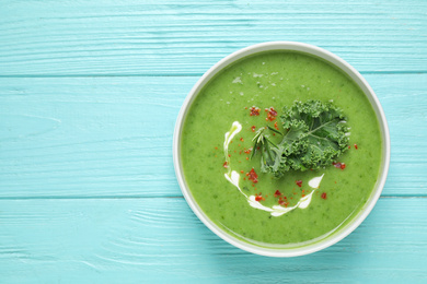 Photo of Tasty kale soup on light blue wooden table, top view. Space for text