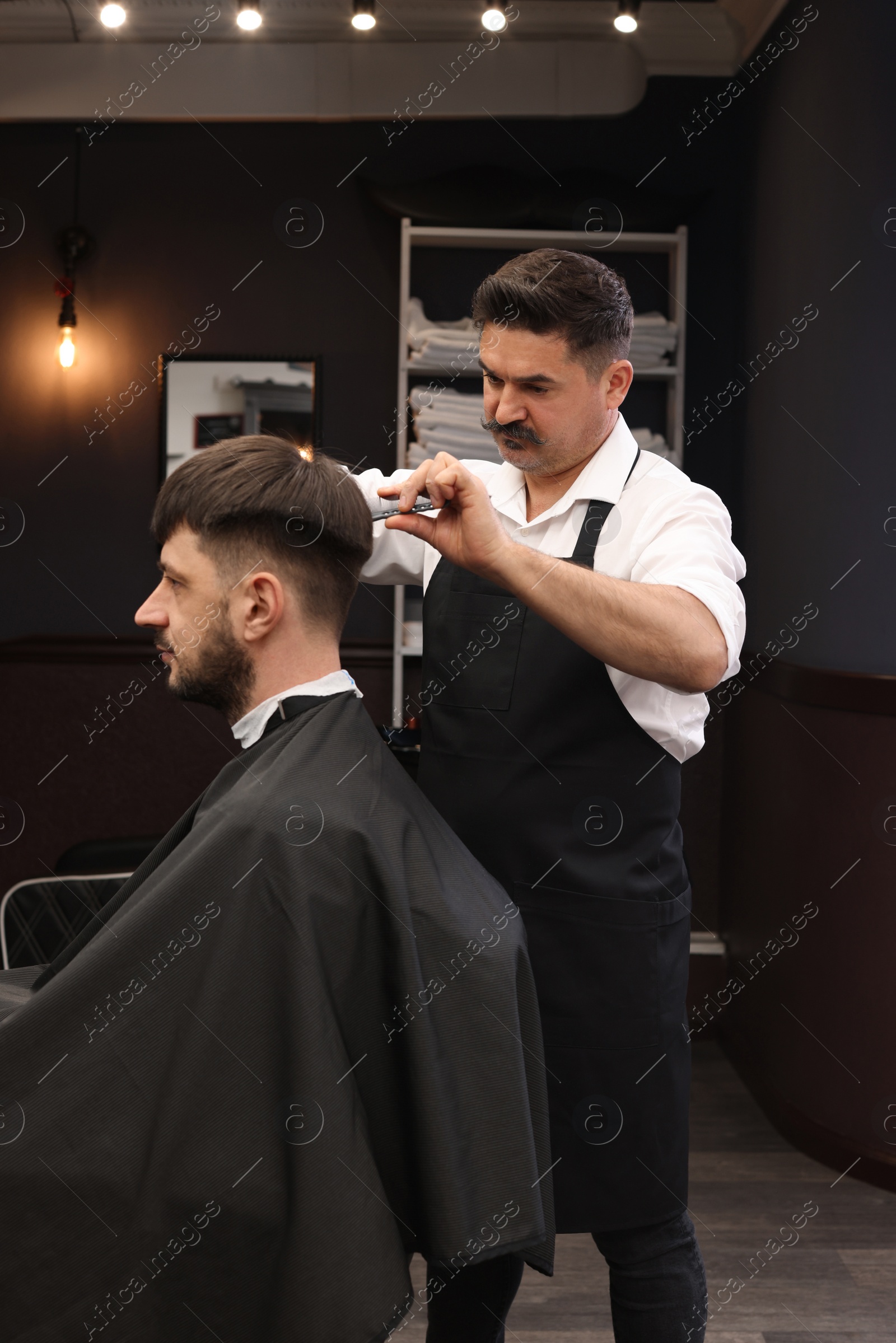 Photo of Professional hairdresser making stylish haircut in barbershop