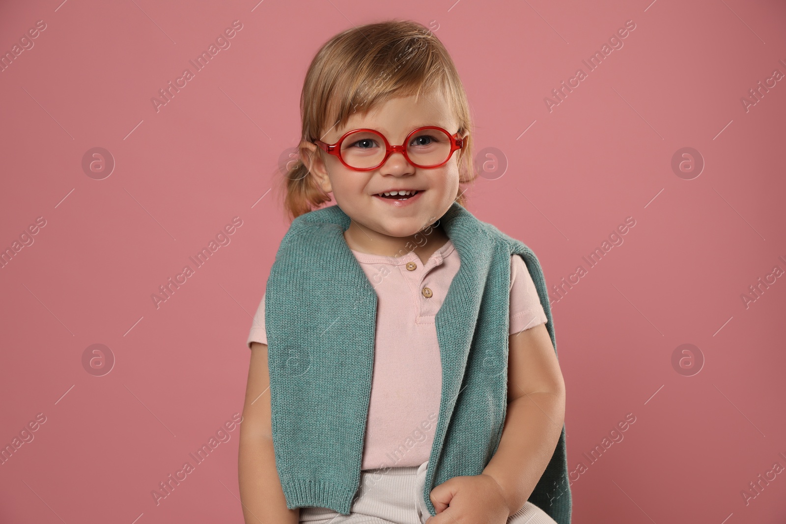 Photo of Cute little girl in glasses on pink background