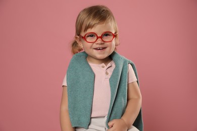 Photo of Cute little girl in glasses on pink background