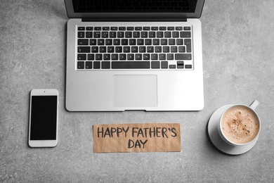 Smartphone, laptop, cup of coffee and card with words HAPPY FATHER'S DAY on grey background, top view