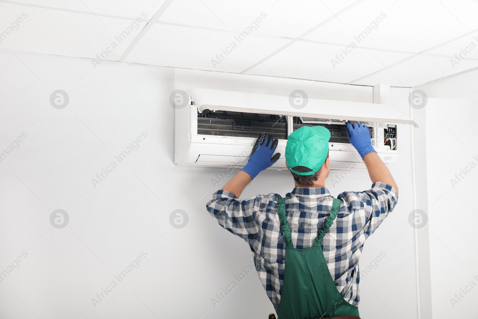 Photo of Male technician cleaning air conditioner indoors