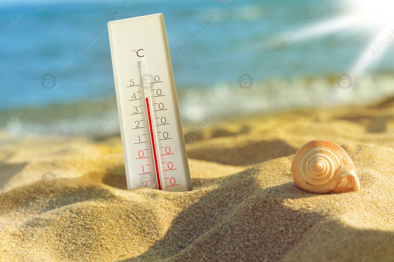 Image of Thermometer on beach showing high temperature during hot day in summer