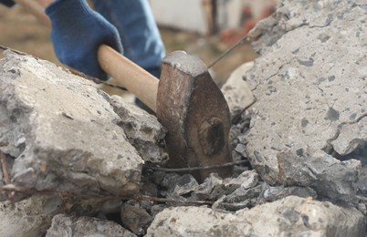 Photo of Man breaking stones with sledgehammer outdoors, closeup