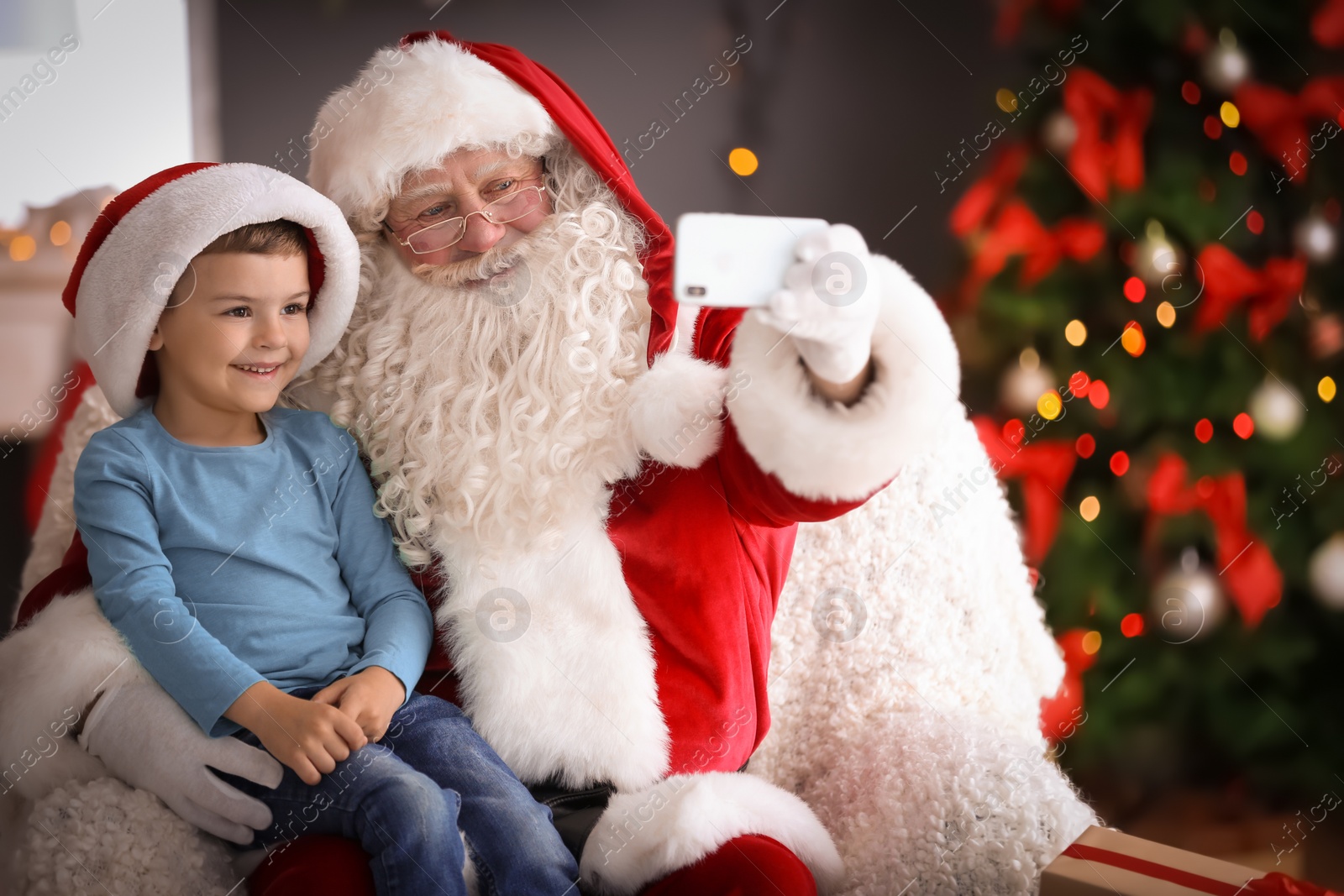 Photo of Authentic Santa Claus taking selfie with little boy indoors