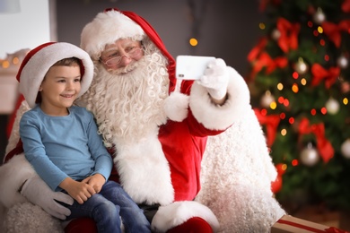 Photo of Authentic Santa Claus taking selfie with little boy indoors