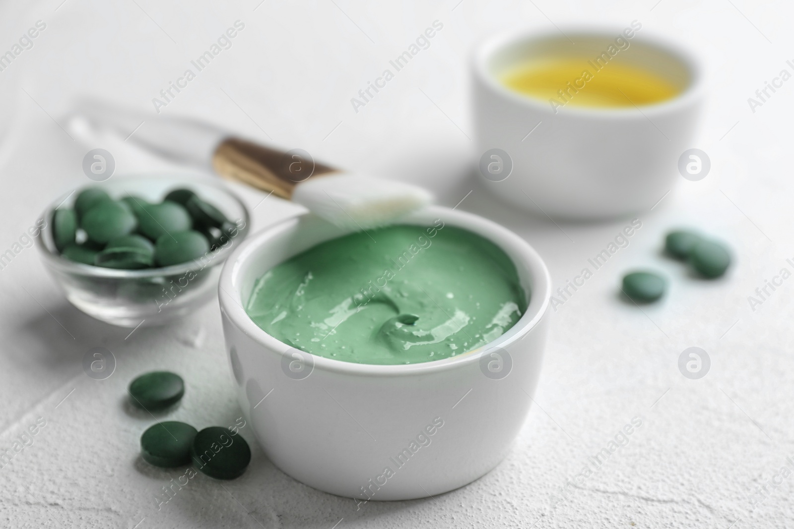 Photo of Spirulina facial mask and brush on white table