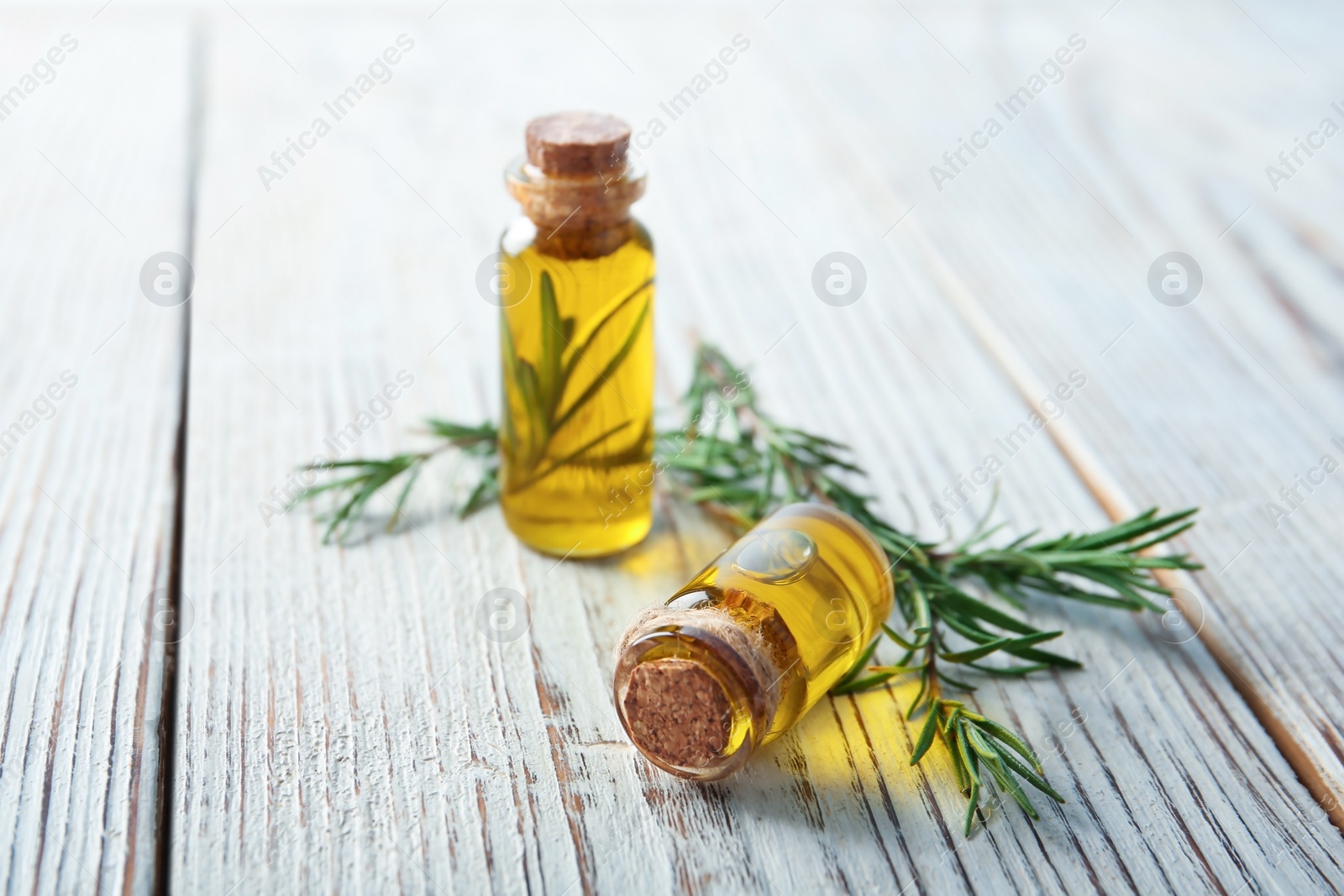 Photo of Bottles with fresh rosemary oil on wooden table