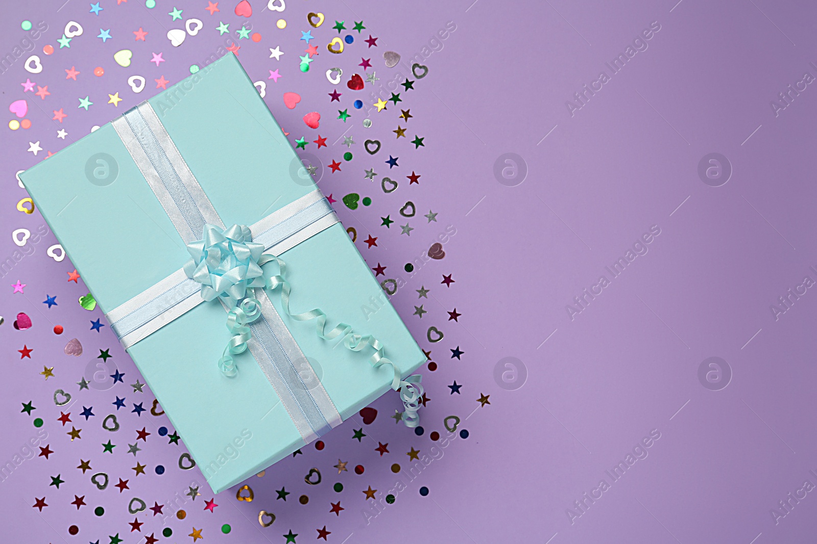 Photo of Light blue gift box and sequins on lilac background, flat lay. Space for text