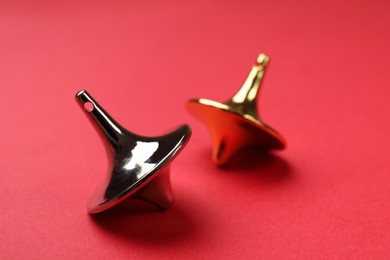 Photo of Golden and silver spinning tops on red background, closeup