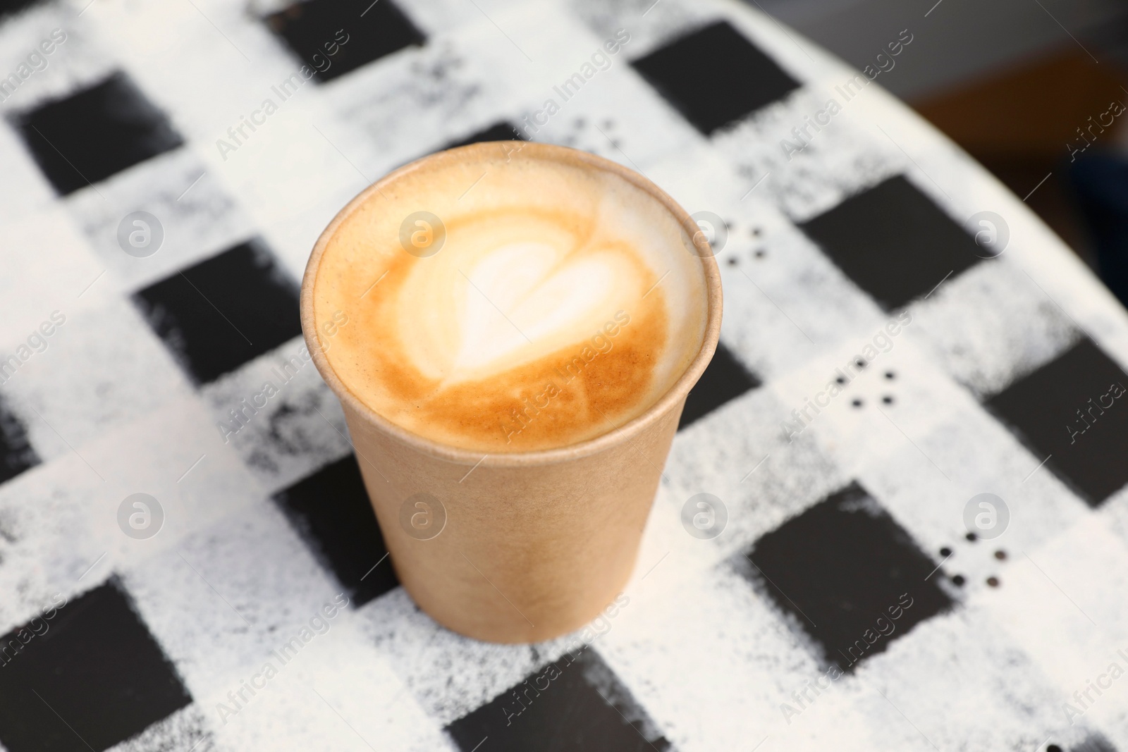 Photo of Takeaway paper cup with hot coffee on table outdoors