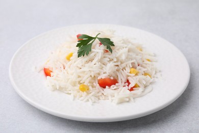 Photo of Delicious rice with vegetables and parsley on light gray table, closeup