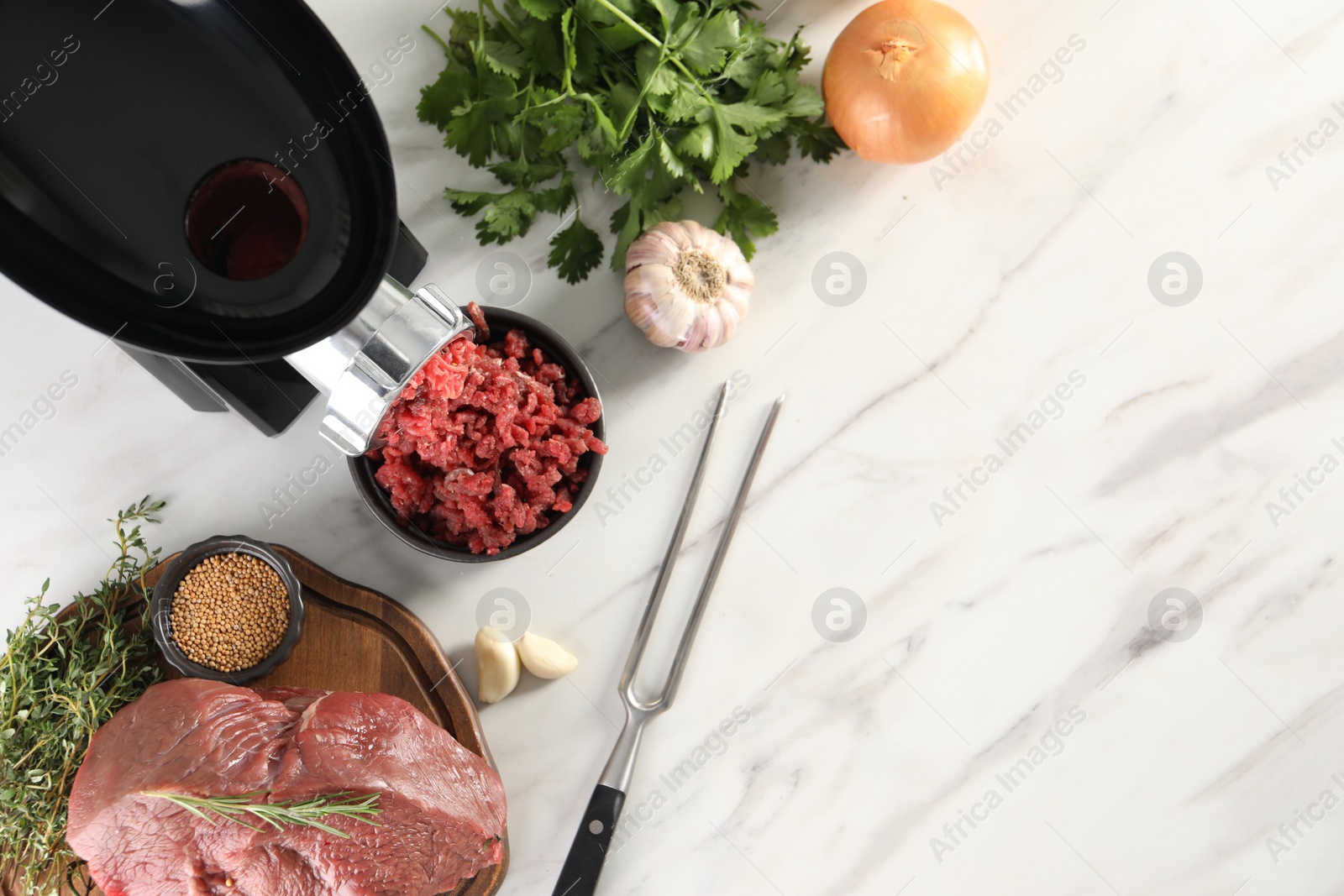 Photo of Electric meat grinder with beef mince and products on white marble table in kitchen, flat lay. Space for text