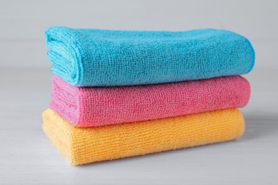 Photo of Stack of colorful microfiber cloths on white table, closeup