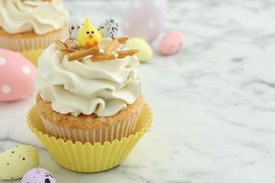 Photo of Tasty Easter cupcake with vanilla cream and candies on white marble table, space for text