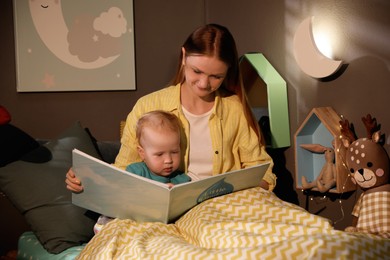 Photo of Mother and child reading book in room with crescent shaped night lamp