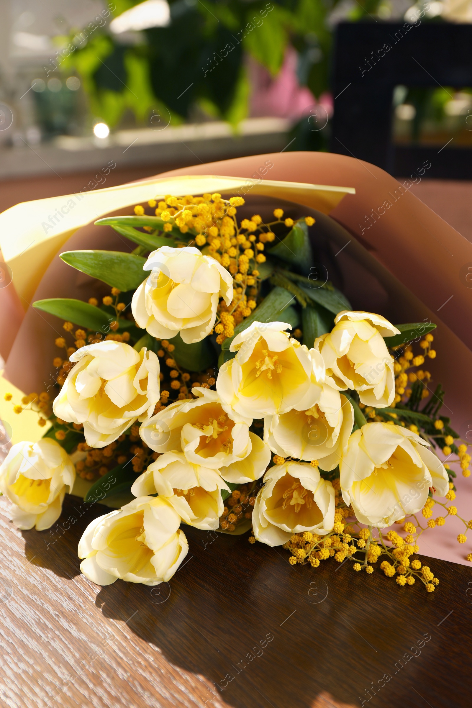 Photo of Bouquet with beautiful tulips and mimosa flowers on wooden table indoors