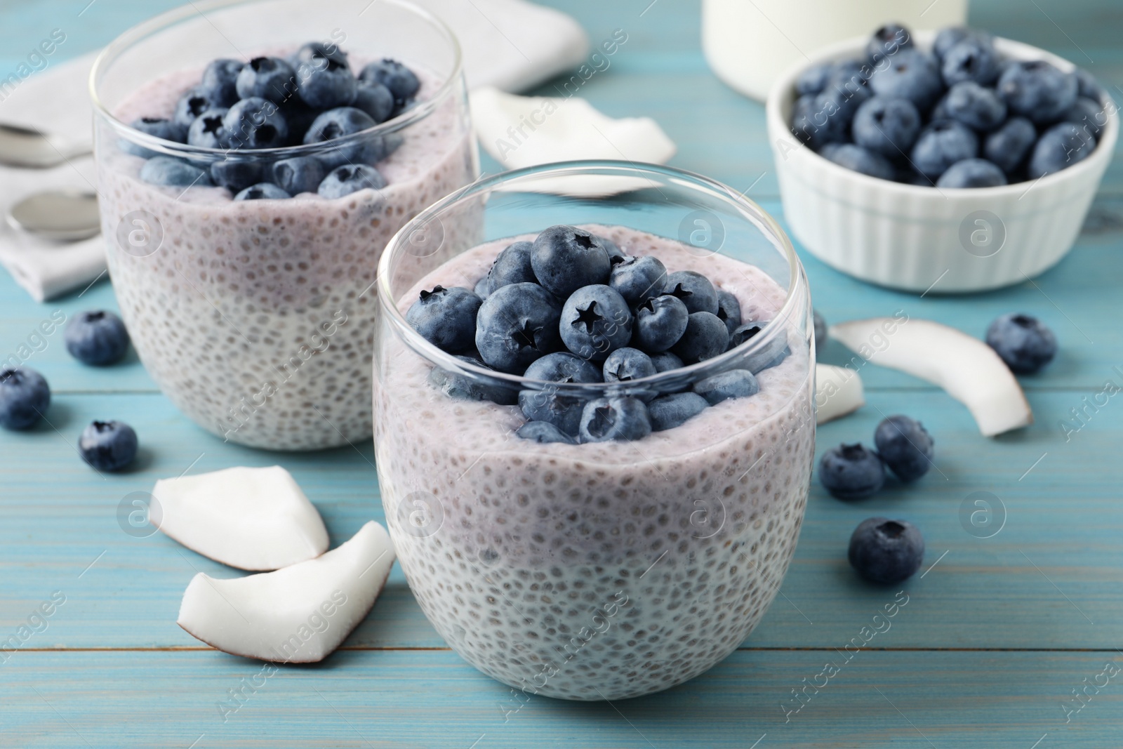 Photo of Delicious chia pudding with blueberries on light blue wooden table
