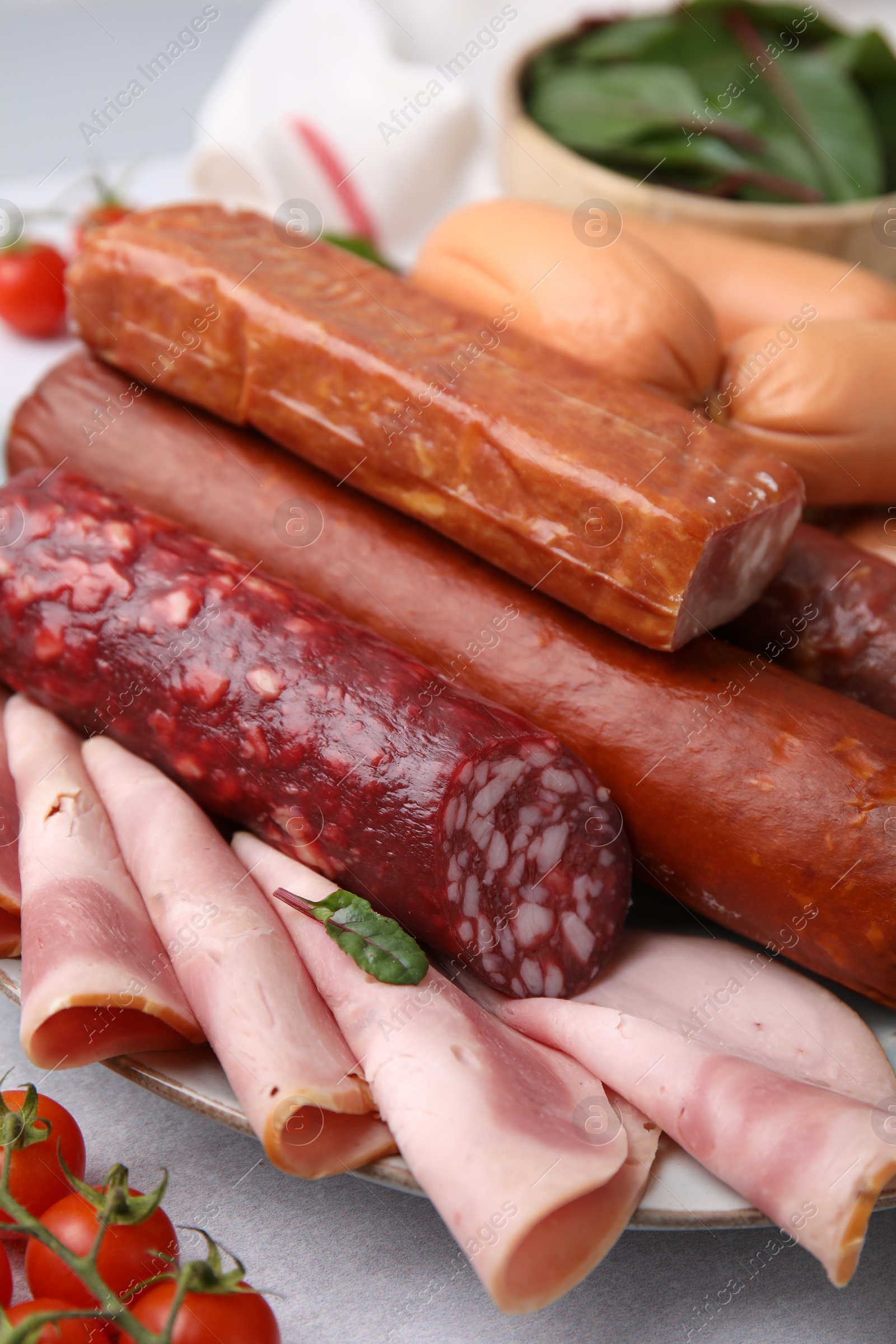 Photo of Different types of tasty sausages and ingredients on white table, closeup