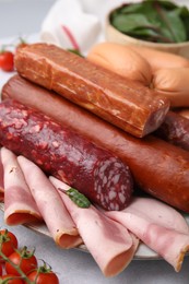 Photo of Different types of tasty sausages and ingredients on white table, closeup