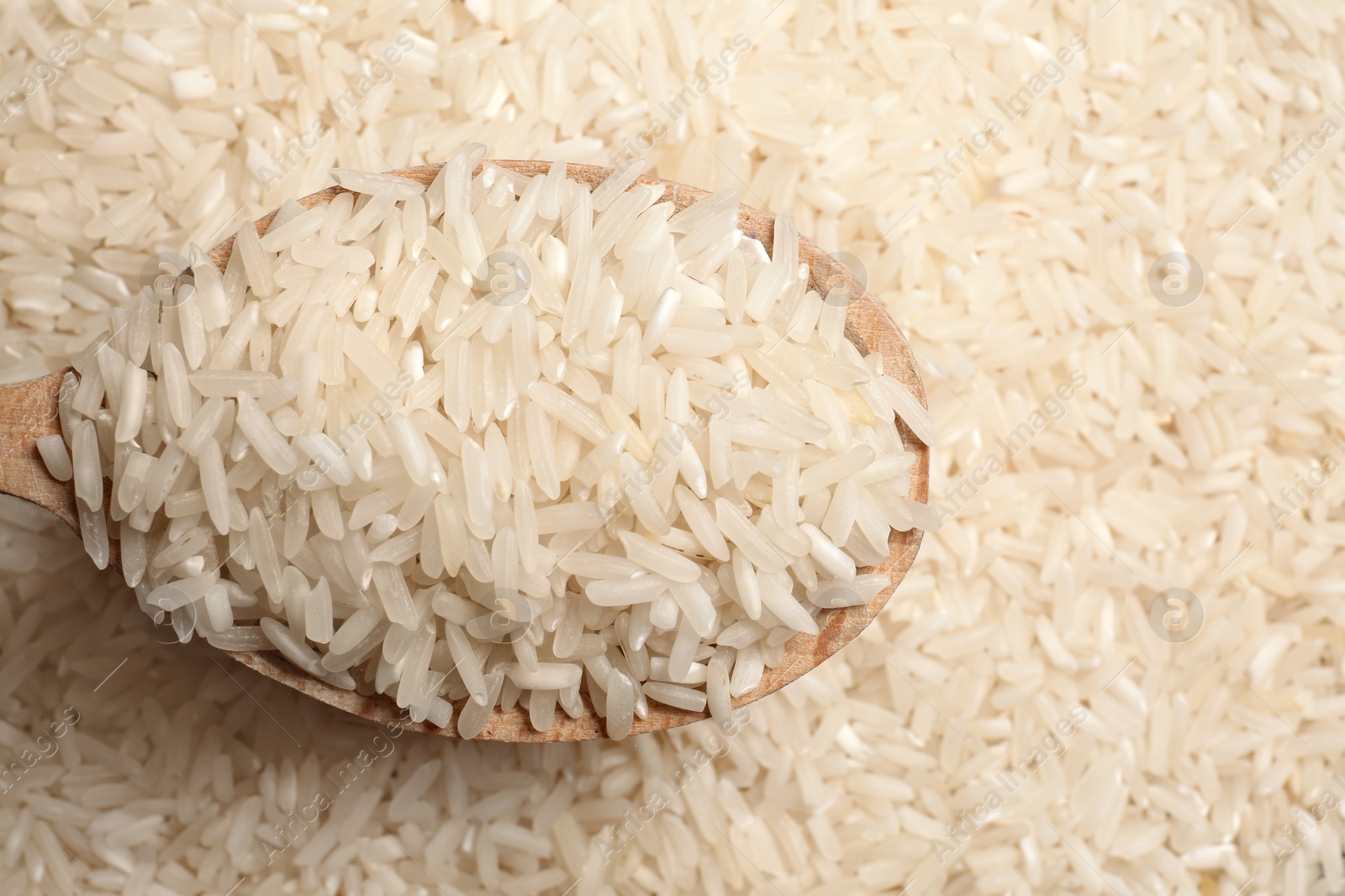 Photo of Long grain rice in wooden spoon, closeup view