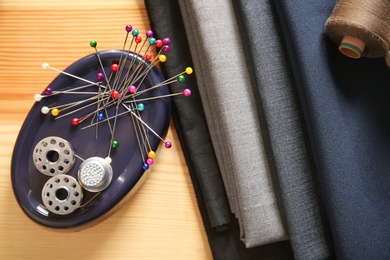 Composition with fabrics and accessories for tailoring on wooden background