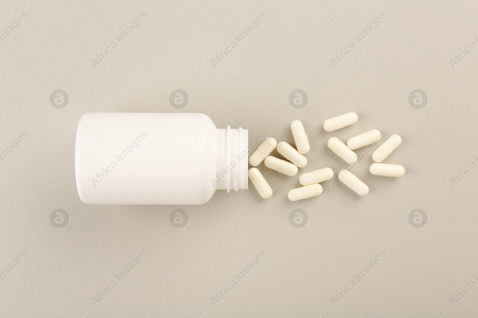 Photo of Bottle and vitamin capsules on light background, top view