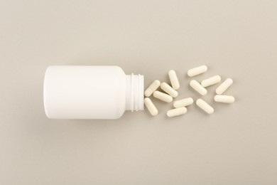 Bottle and vitamin capsules on light background, top view