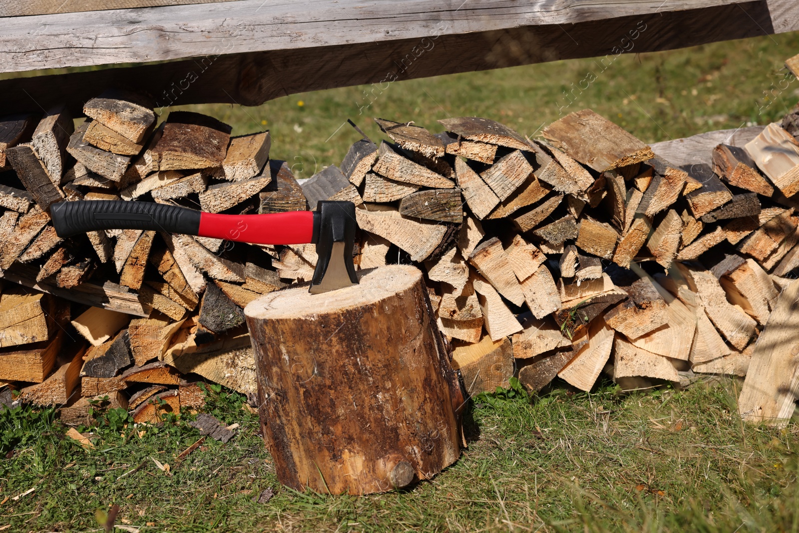 Photo of Tree stump with axe and cut firewood outdoors