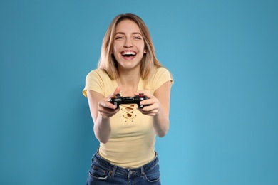 Photo of Emotional young woman playing video games with controller on color background. Space for text