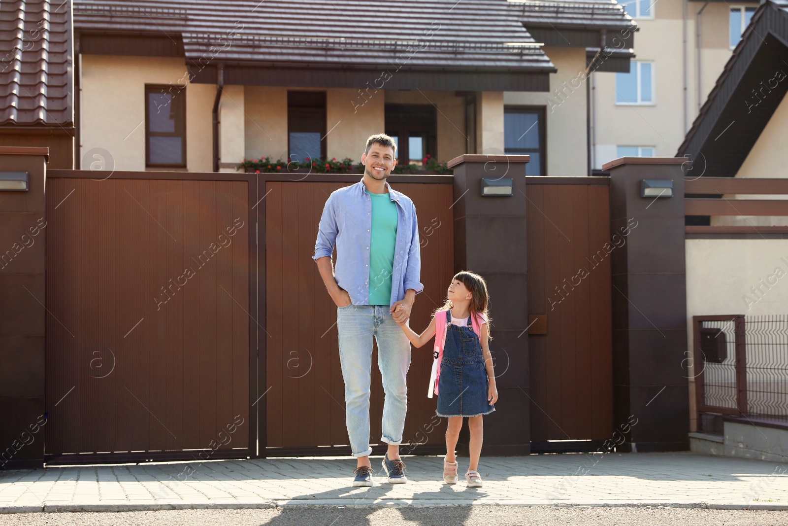 Photo of Happy father taking his little child to school on street