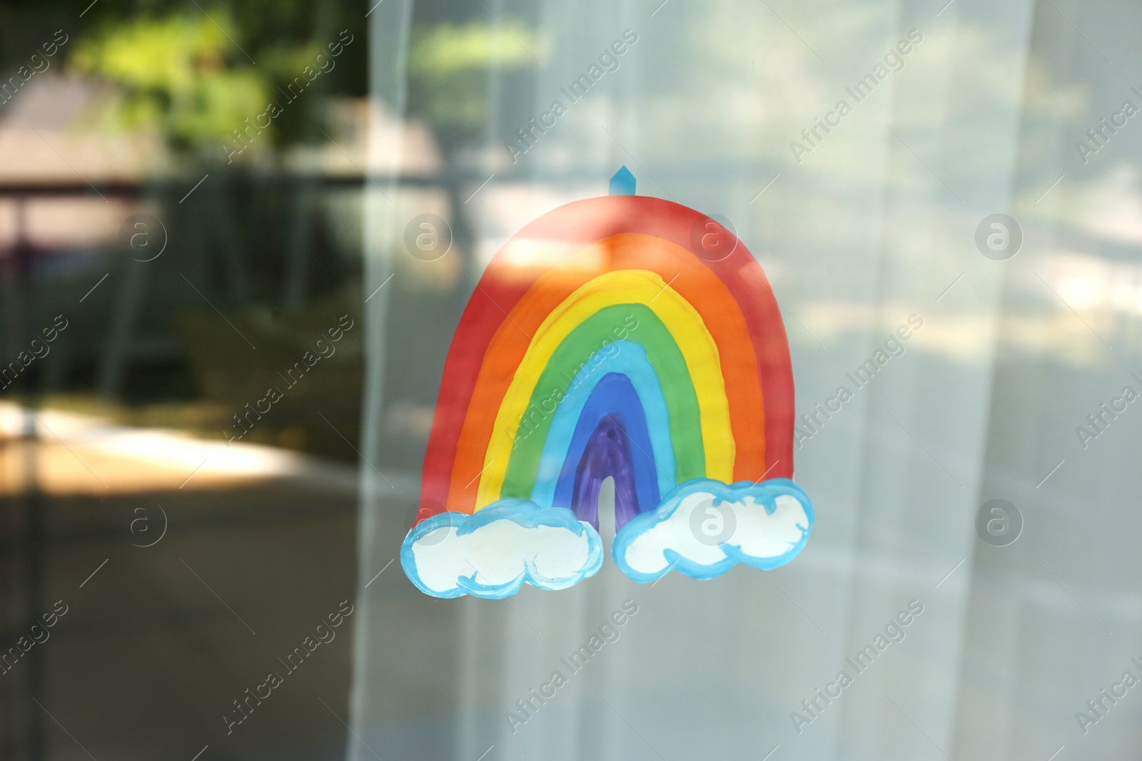Photo of Picture of rainbow on window, view from outdoors. Stay at home concept