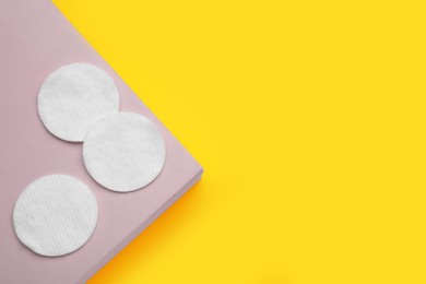 Photo of Soft clean cotton pads on yellow background, top view. Space for text