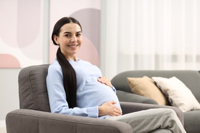 Photo of Happy pregnant woman on armchair at home