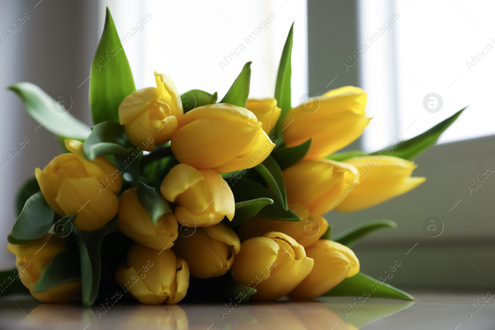 Photo of Bunch of beautiful yellow tulip flowers on windowsill, closeup